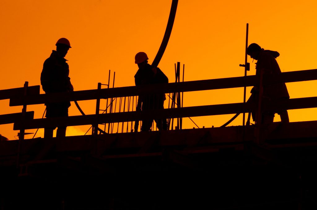 夕陽を背景とした工事現場で作業する人々のシルエット